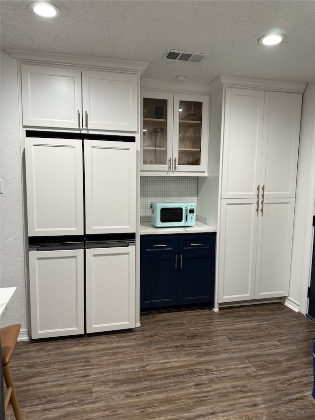 bar featuring white microwave, recessed lighting, dark wood-type flooring, visible vents, and tasteful backsplash