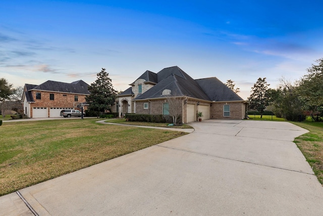 view of front of house with driveway, a front lawn, an attached garage, and brick siding