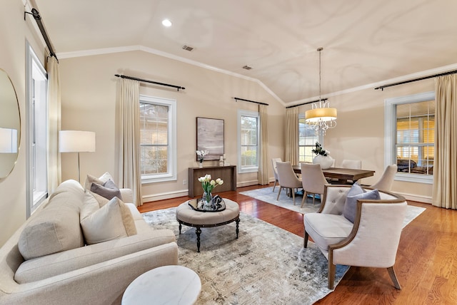 living area featuring vaulted ceiling, ornamental molding, and wood finished floors