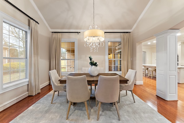 dining space with a notable chandelier, wood finished floors, a wealth of natural light, and crown molding