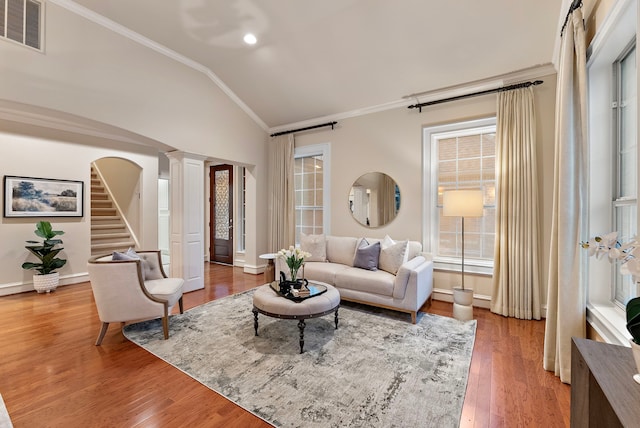 living room featuring decorative columns, visible vents, ornamental molding, wood finished floors, and vaulted ceiling