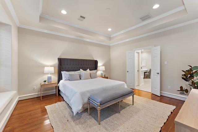 bedroom with wood-type flooring, visible vents, a raised ceiling, and ornamental molding