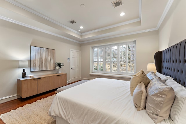 bedroom with visible vents, a raised ceiling, ornamental molding, and dark wood-style flooring