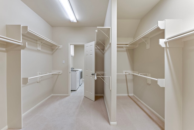 spacious closet with washing machine and clothes dryer and light colored carpet