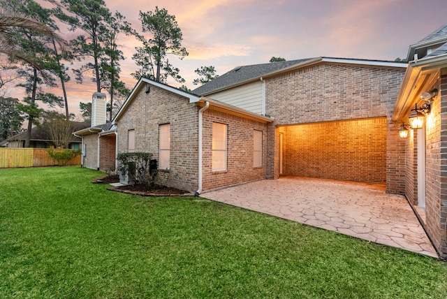 back of house featuring brick siding, a yard, fence, and a patio