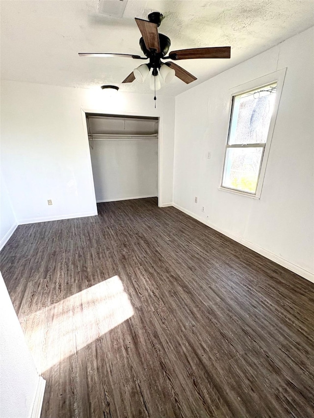 unfurnished bedroom featuring baseboards, visible vents, dark wood-style flooring, a textured ceiling, and a closet