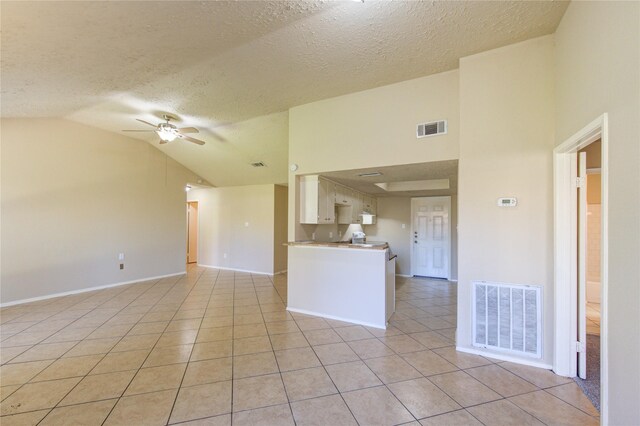 empty room featuring lofted ceiling, visible vents, ceiling fan, and light tile patterned flooring