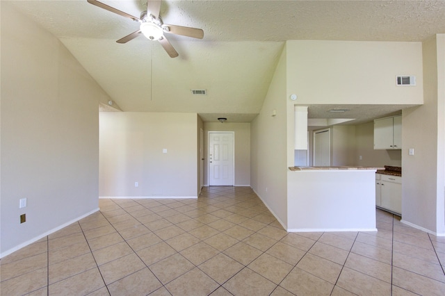 unfurnished room featuring visible vents, ceiling fan, vaulted ceiling, a textured ceiling, and light tile patterned flooring