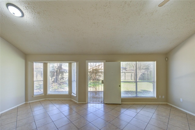 unfurnished room featuring a textured ceiling, tile patterned flooring, and baseboards