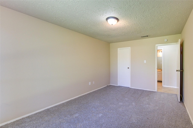 unfurnished bedroom with light carpet, a textured ceiling, visible vents, and baseboards