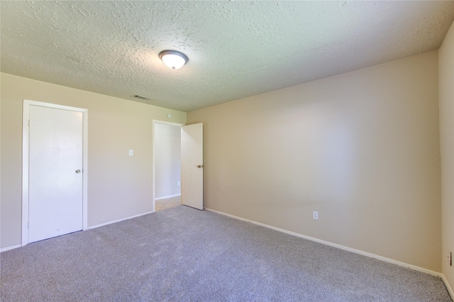 unfurnished bedroom featuring baseboards, a textured ceiling, visible vents, and carpet flooring