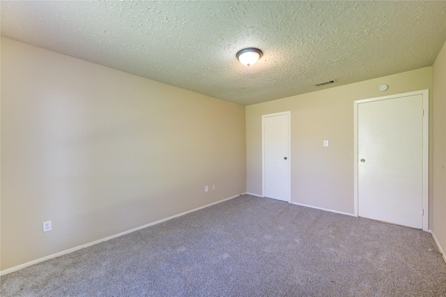 unfurnished bedroom with baseboards, a textured ceiling, visible vents, and carpet flooring