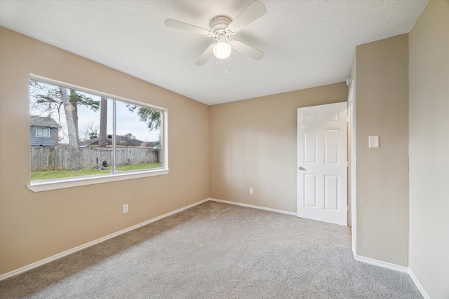 carpeted empty room with baseboards, a textured ceiling, and a ceiling fan