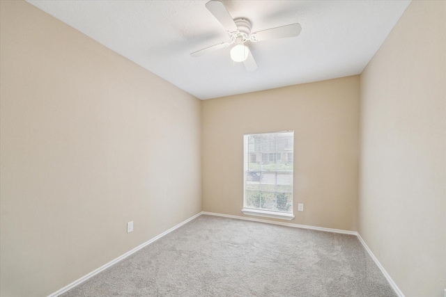 carpeted spare room with baseboards and a ceiling fan