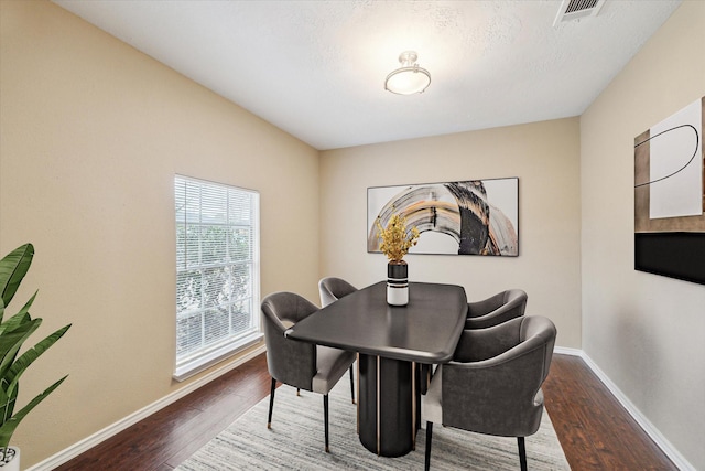 dining area with wood finished floors, visible vents, and baseboards