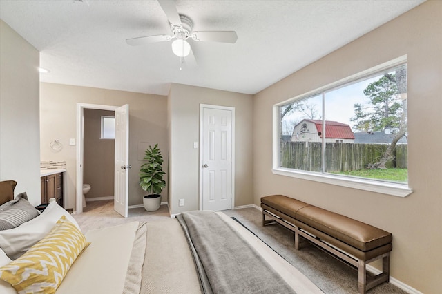 bedroom featuring ensuite bath, a ceiling fan, baseboards, and light carpet