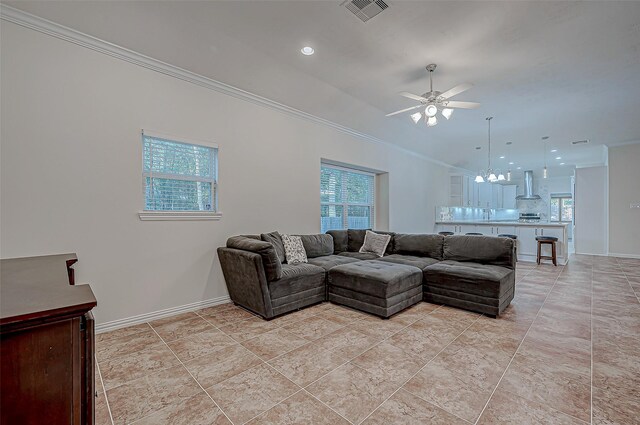 living area with a wealth of natural light, ornamental molding, visible vents, and baseboards