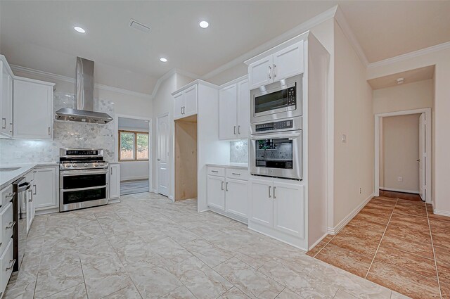 kitchen with white cabinets, decorative backsplash, wall chimney exhaust hood, stainless steel appliances, and light countertops