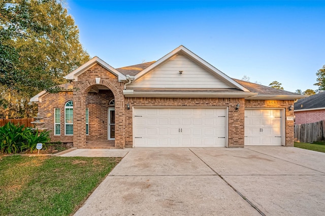 view of front of home with brick siding, fence, driveway, and an attached garage