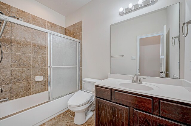 bathroom featuring combined bath / shower with glass door, vanity, toilet, and tile patterned floors