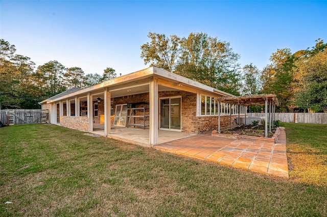 rear view of property featuring brick siding, a yard, a patio, a pergola, and a fenced backyard