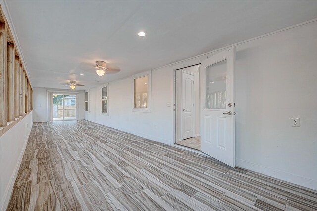 unfurnished living room with light wood-type flooring, ceiling fan, and baseboards