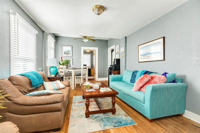 living area featuring a ceiling fan, baseboards, and wood finished floors