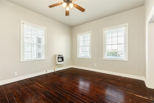 empty room featuring heating unit, ceiling fan, baseboards, and dark wood-type flooring