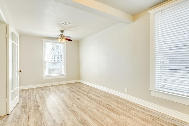 spare room with light wood finished floors, a ceiling fan, visible vents, and baseboards