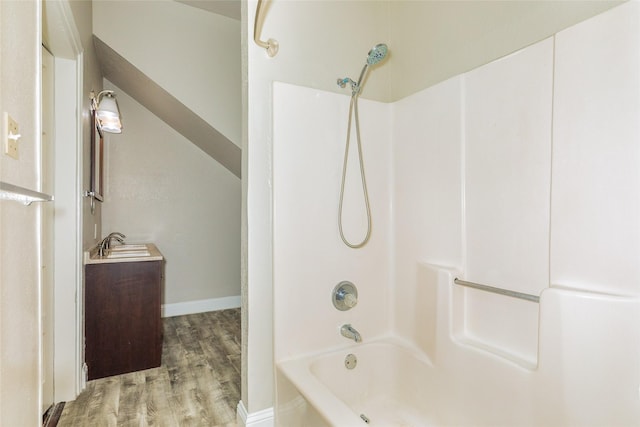 bathroom with a sink, bathing tub / shower combination, baseboards, and wood finished floors