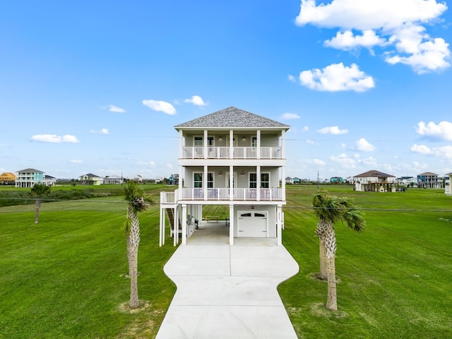 raised beach house featuring a balcony, driveway, a carport, and a front yard