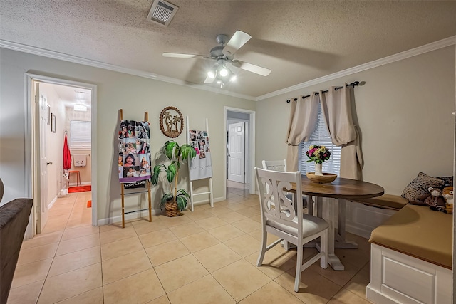 dining area with visible vents, ceiling fan, a textured ceiling, crown molding, and light tile patterned flooring