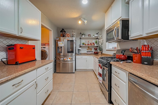 kitchen featuring light tile patterned floors, washer / clothes dryer, stainless steel appliances, light countertops, and white cabinetry