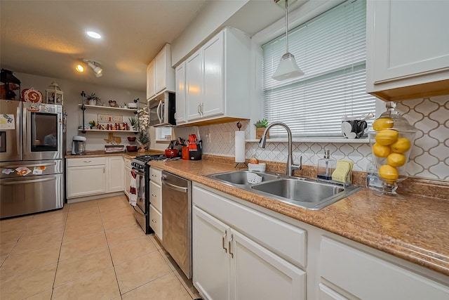 kitchen featuring light tile patterned floors, appliances with stainless steel finishes, a sink, and white cabinetry