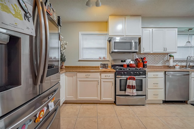 kitchen featuring stainless steel appliances, light tile patterned flooring, a sink, and tasteful backsplash