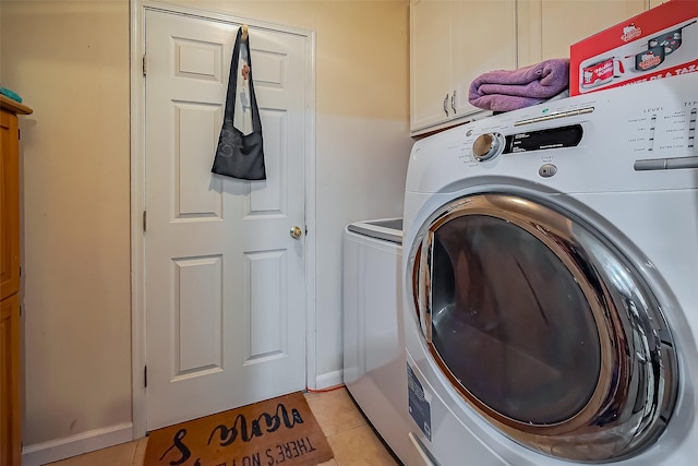 washroom with washing machine and dryer, cabinet space, and light tile patterned floors