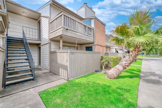 view of side of property with a yard and a balcony