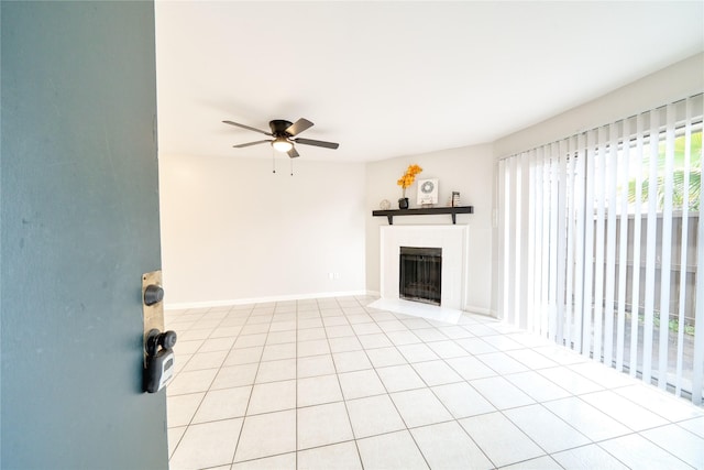 unfurnished living room with ceiling fan, a fireplace, baseboards, and light tile patterned flooring