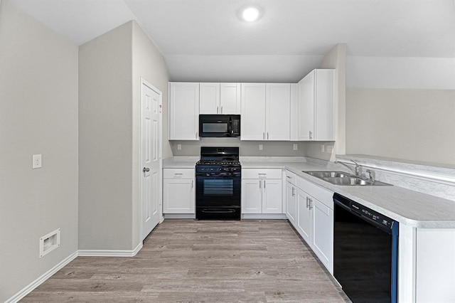 kitchen with light wood-style floors, light countertops, black appliances, white cabinetry, and a sink