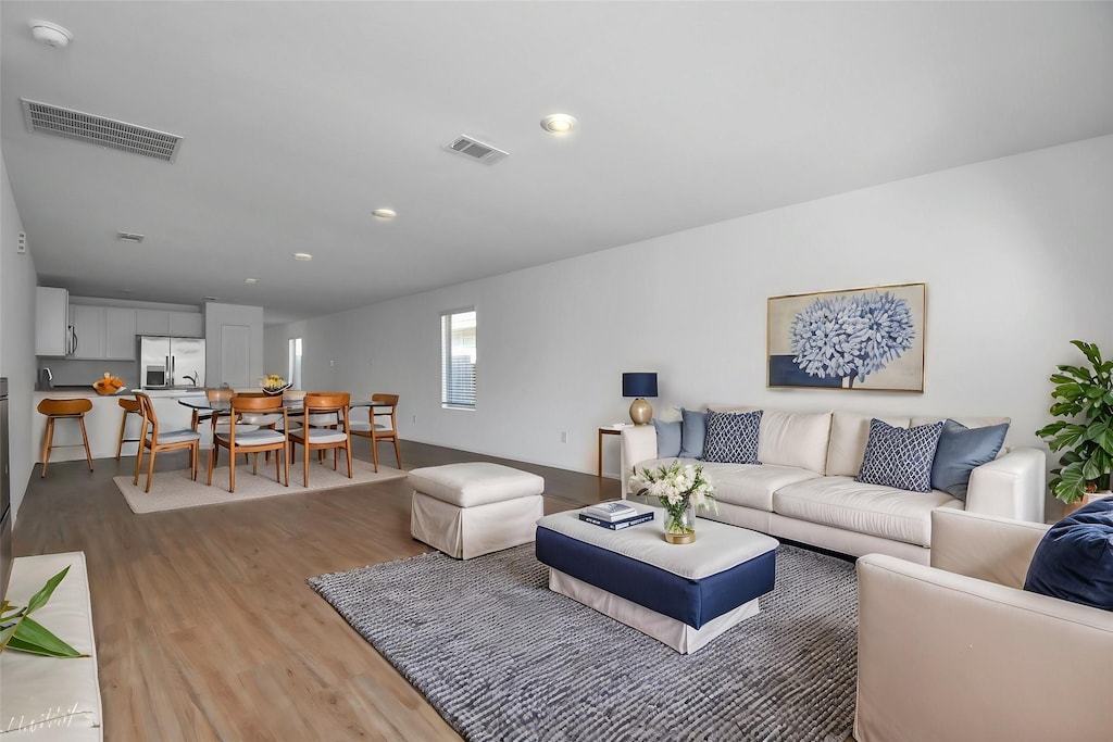 living room with recessed lighting, visible vents, and light wood finished floors