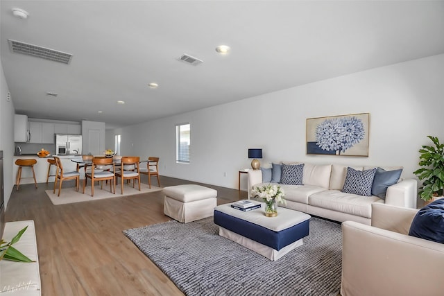 living room with recessed lighting, visible vents, and light wood finished floors