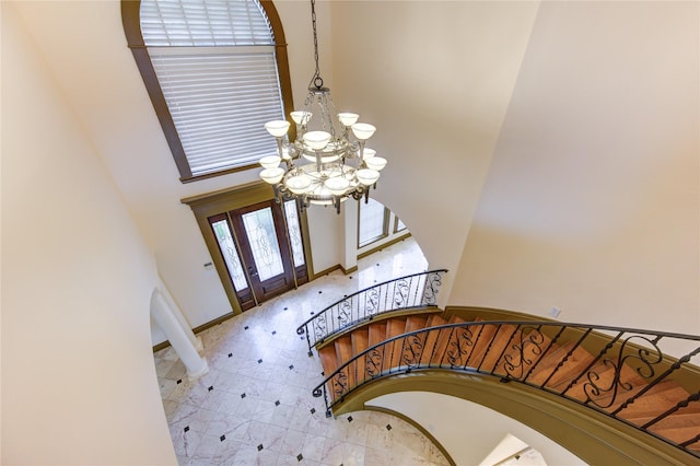 foyer entrance featuring stairway, a high ceiling, an inviting chandelier, baseboards, and tile patterned floors