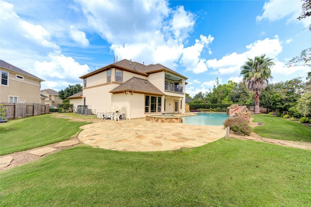 rear view of property with a balcony, a yard, a patio area, and an in ground hot tub