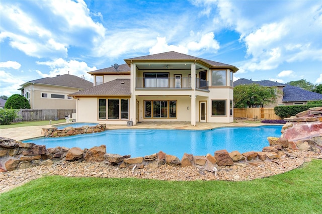 back of property with an in ground hot tub, a fenced backyard, a balcony, and stucco siding