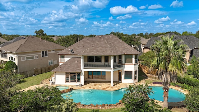 rear view of house featuring a fenced backyard, a balcony, a lawn, stucco siding, and a patio area