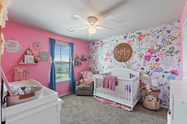 bedroom with a ceiling fan, a nursery area, visible vents, and carpet flooring