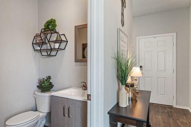 half bathroom featuring vanity, toilet, and wood finished floors