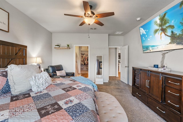 bedroom featuring dark colored carpet, a walk in closet, visible vents, and a ceiling fan