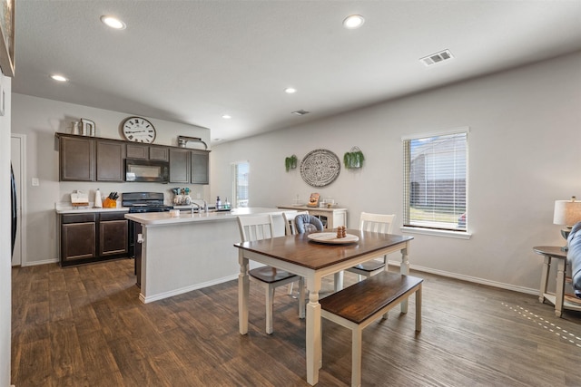 kitchen featuring dark wood finished floors, light countertops, visible vents, dark brown cabinets, and black appliances