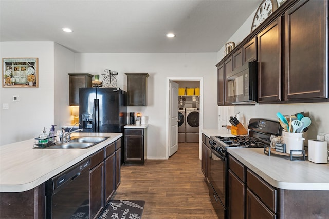 kitchen featuring dark brown cabinetry, a sink, washer and clothes dryer, and black appliances